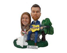 Custom Bobblehead Man Sitting On A Rock Holding Guitar Playing For His Wife Who Is Sitting Next To Him In A Gown - Wedding & Couples Couple Personalized Bobblehead & Cake Topper